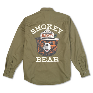 An olive green long-sleeve button-up shirt shown from the back, featuring a large graphic of the Smokey Bear mascot with the words 'SMOKEY BEAR' printed in cream above and below.