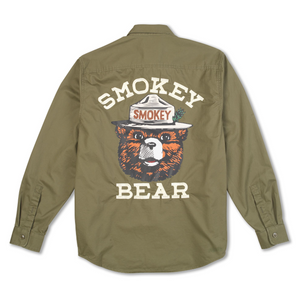 An olive green long-sleeve button-up shirt shown from the back, featuring a large graphic of the Smokey Bear mascot with the words 'SMOKEY BEAR' printed in cream above and below.