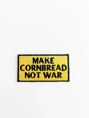 Embroidered patch with 'MAKE CORNBREAD NOT WAR' text on a yellow background