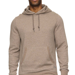 Man wearing a beige hoodie and blue jeans on a white background