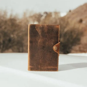 Antique brown leather journal with snap button closure, displayed against a natural background.